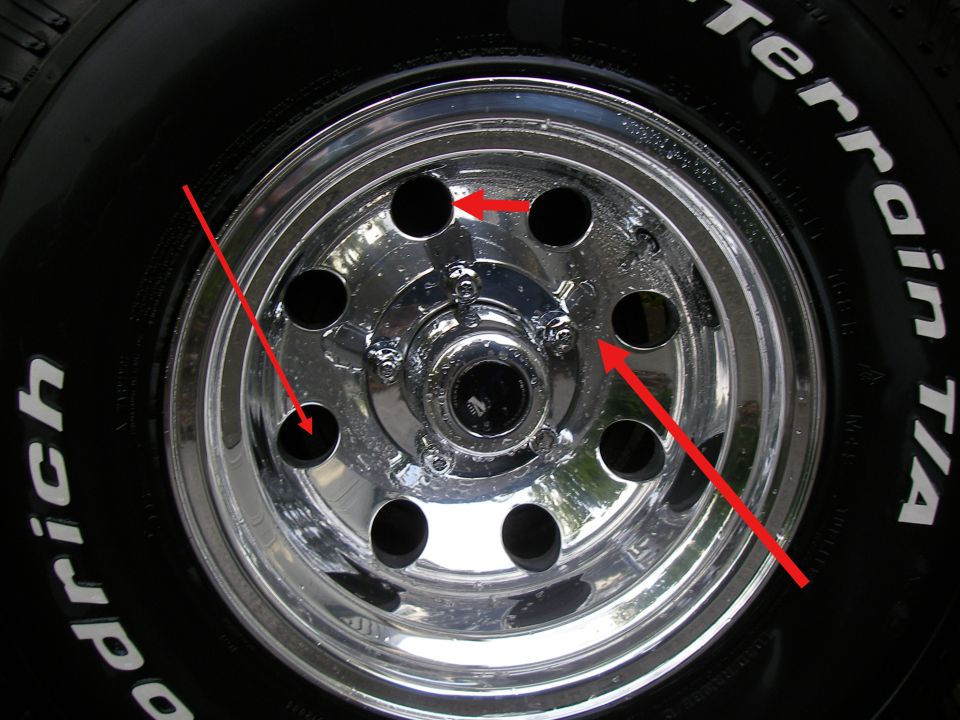 Polished eight-hole aluminum wheel with BFGoodrich All-Terrain tire, red arrows marking spots on the wheel