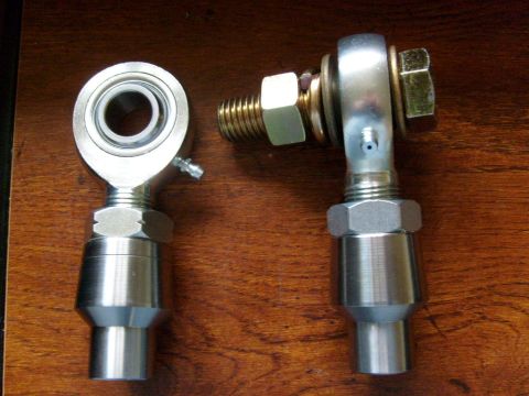 1994 Ford Bronco - Close-up of two metal rod end bearings with threaded shafts resting on a wooden surface.