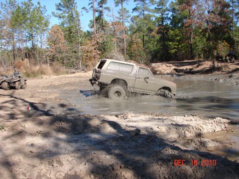 1987 Ford Bronco - 1987 Ford Bronco navigating a mud pit, with an ATV visible in the background.