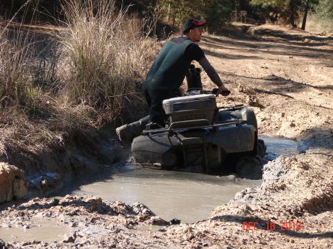 1987 Ford Bronco - A rider navigates an all-terrain vehicle through a muddy trail.