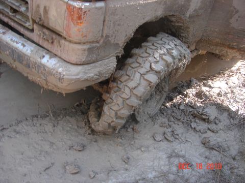 1987 Ford Bronco - A 1987 Ford Bronco is stuck in deep mud, with its front wheel submerged.