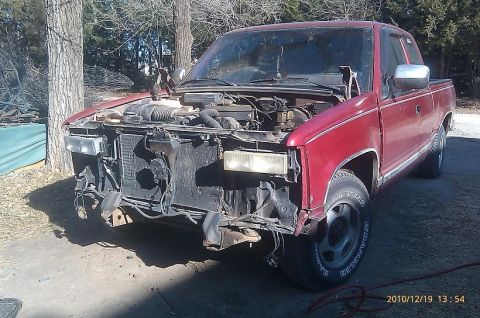 2000 Mercury Grand Marquis - This red pickup truck is missing its front bumper and grille, revealing the engine bay.