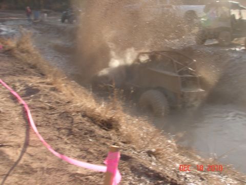 1987 Ford Bronco - An off-road buggy navigates a muddy obstacle course, kicking up a large spray of mud.