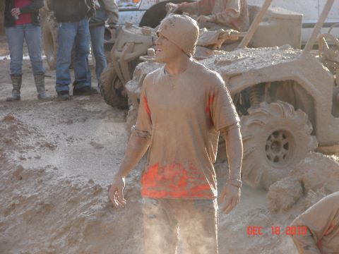 1987 Ford Bronco - A group of people covered in mud stand around ATVs in a muddy environment, with a watermark indicating Supermotors.net.