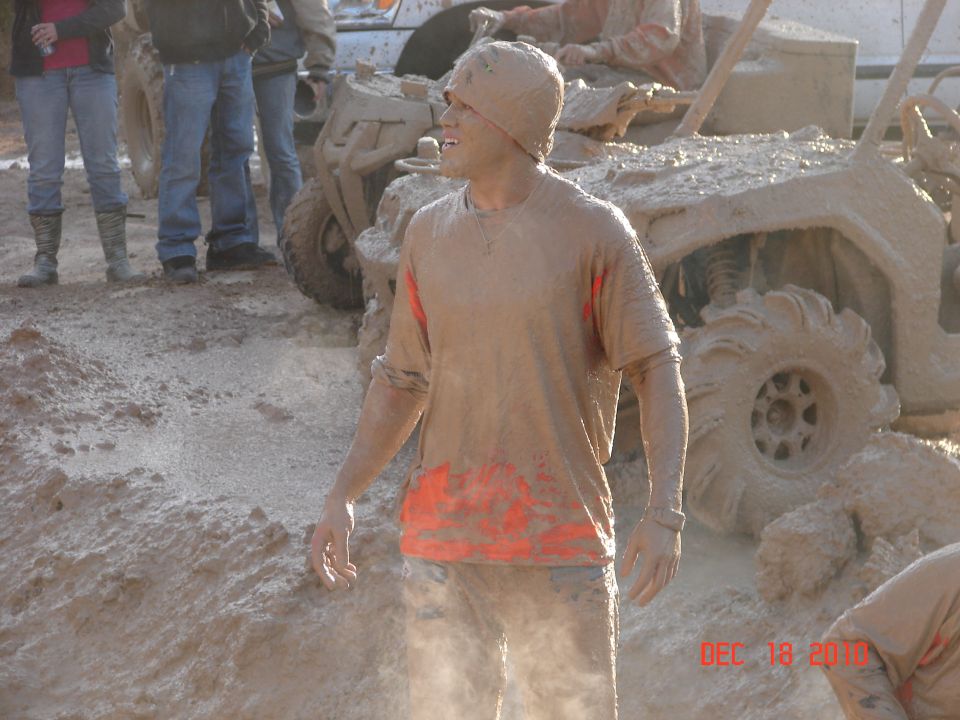 Muddy people and ATVs in a muddy scene with Supermotors.net watermark