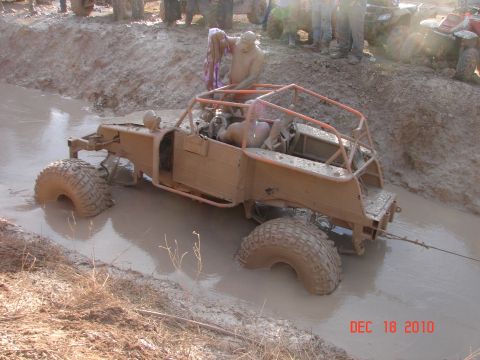 1987 Ford Bronco - This off-road buggy is deep in the mud, with onlookers gathered around.