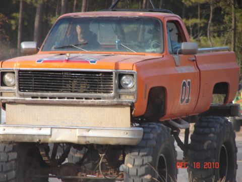 1987 Ford Bronco - This lifted pickup truck, likely a 1973-1987 Chevrolet C/K series, features a "01" decal on the door and a Confederate flag decal on the ho…