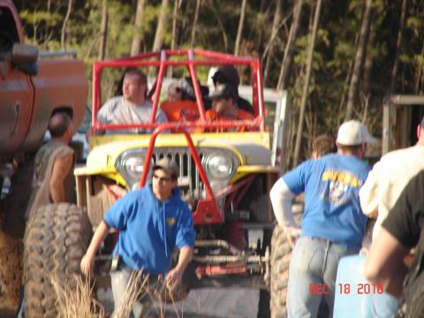 1987 Ford Bronco - Several people are gathered around a yellow jeep with a red roll cage, possibly at an off-road event.