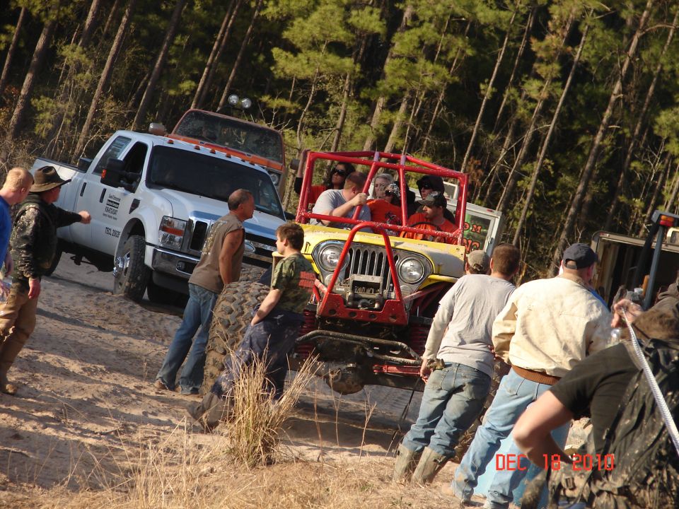 Yellow jeep with red roll cage and large tires on a dirt path