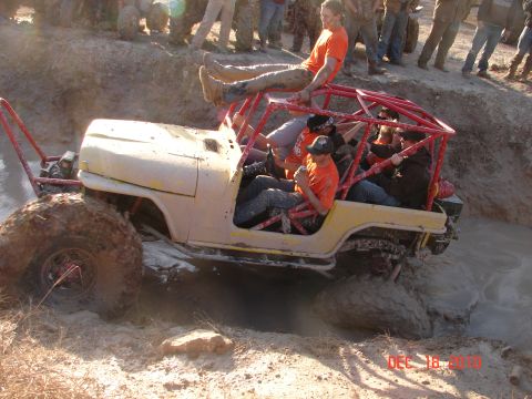 1987 Ford Bronco - A group of people are enjoying a muddy off-road adventure in a modified vehicle.