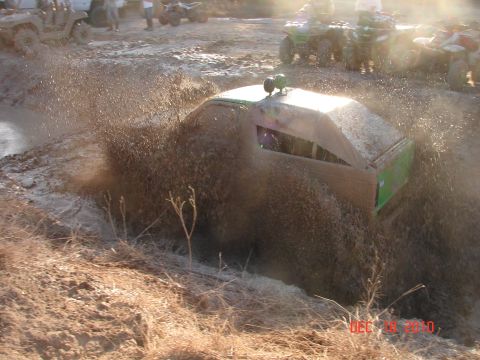 1987 Ford Bronco - Custom vehicle navigating a muddy obstacle course with ATVs visible in the background.