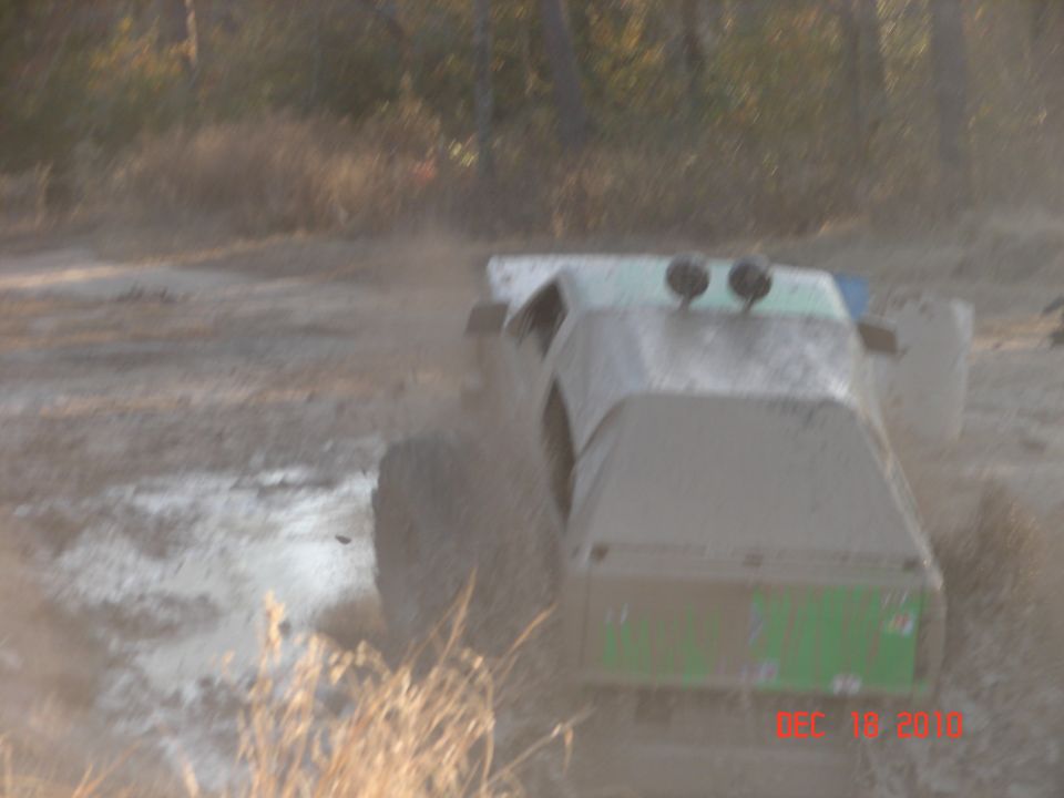 Muddy off-road vehicle with two lights on top, kicking up dust