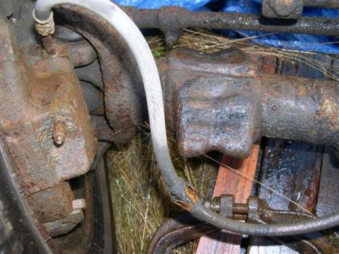 1982 Ford Bronco - Rusted vehicle axle and brake components are visible in this close-up shot. Text on the brake line indicates a date of 02/10/98.