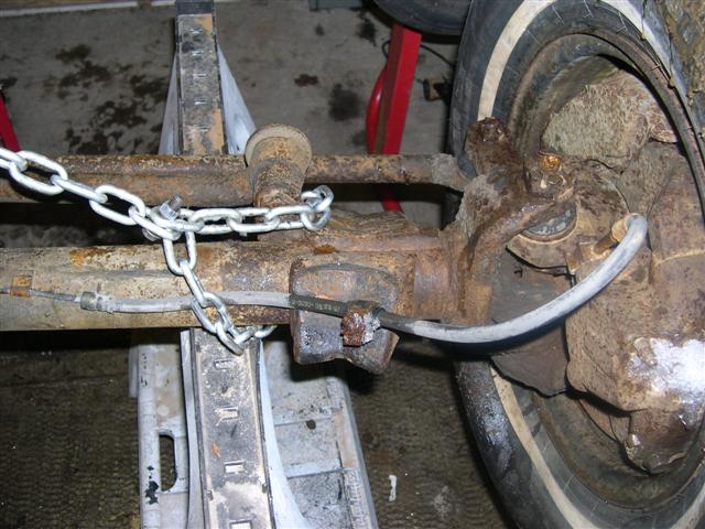 Rusty suspension part with chain and tire on jack stands