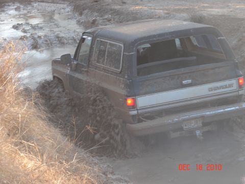 1987 Ford Bronco - This Chevrolet K5 Blazer is navigating a muddy trail, kicking up a lot of dirt.