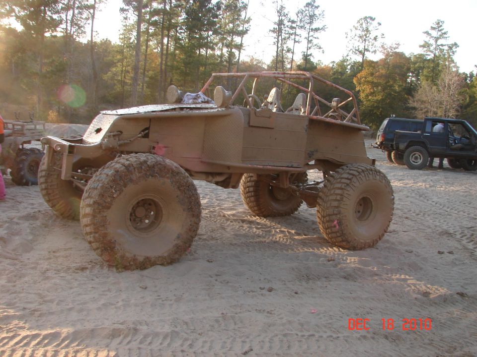 Custom off-road buggy with large tires and roll cage, seen from the front-right