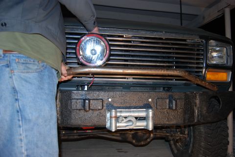 1982 Ford Bronco - Front view of a truck's bumper, grille, and a spotlight being installed.