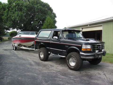 1995 Ford Bronco - Black 1995 Ford Bronco with a boat on a trailer parked in front of a garage.