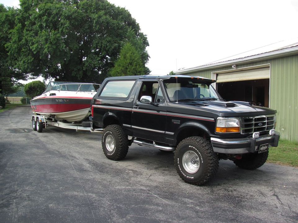 1995 Ford Bronco towing a red and white boat on a trailer