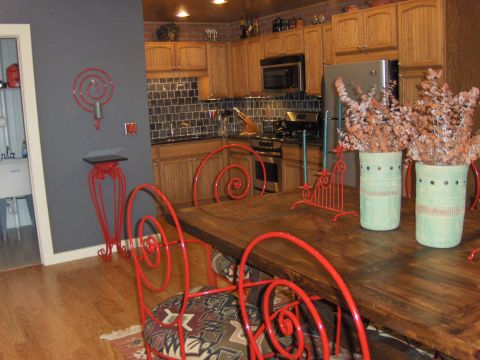 1979 Chevrolet Camaro - A view of a kitchen and dining area, showing wooden cabinets, a tiled backsplash, and red chairs around a wooden table.