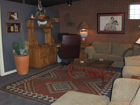 1979 Chevrolet Camaro - Interior scene of a living room a couch, coffee table, and desk area with a brick wall backdrop.