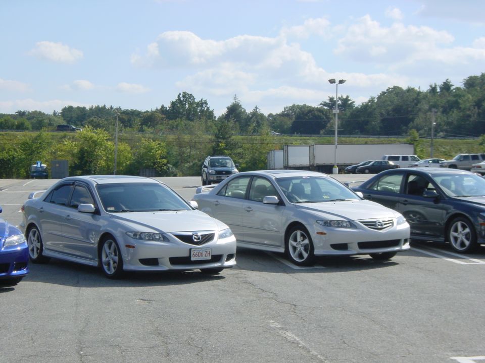 Two silver Mazda 6 sedans parked side by side at an outdoor car meet