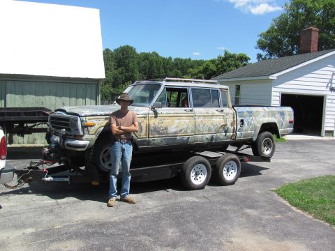 1986 Jeep Grand Wagoneer - A custom-built, extended cab pickup truck is loaded onto a trailer in front of a residential garage.