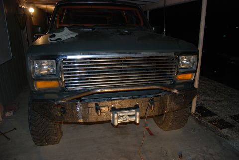 1982 Ford Bronco - Front view of a dark green 1982 Ford Bronco, a chrome grille and an aftermarket winch bumper.