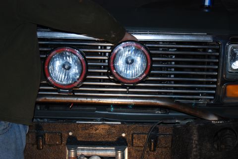 1982 Ford Bronco - Auxiliary lights are being installed on the front grille of a vehicle.
