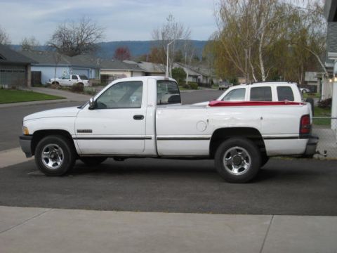 1976 Ford F-250 - A white 1994 Dodge Ram pickup truck is shown from the side, with a red-topped SUV loaded in its bed.