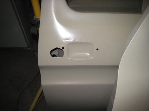 1976 Ford F-250 - Close-up of a vehicle door panel, likely undergoing restoration or repair, with visible primer.