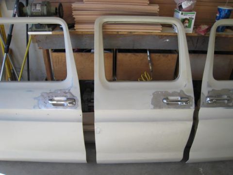 1976 Ford F-250 - Workshop scene showing multiple truck doors undergoing repair or preparation.