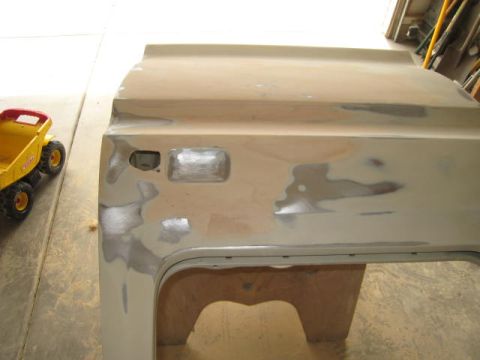 1976 Ford F-250 - A truck door is being prepped for paint, showing areas of body filler and primer.