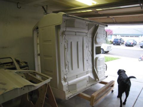 1976 Ford F-250 - A truck cab body is being worked on inside a garage, with other vehicles visible through the open garage door.