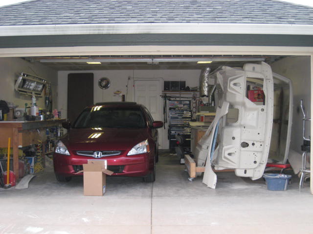 Red Honda Accord parked in garage next to a white car body shell on a stand