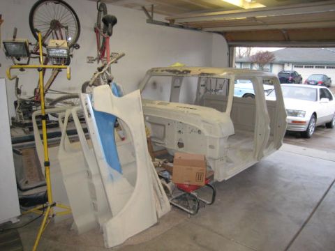 1976 Ford F-250 - A 1976 Ford F-250 truck cab and detached fender are disassembled in a garage, awaiting restoration.