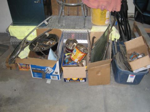 1976 Ford F-250 - Various automotive parts are organized in boxes and containers within a garage setting.