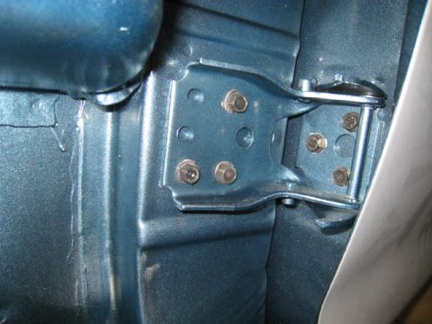 1976 Ford F-250 - Close-up of the door hinge mechanism on a blue 1976 Ford F-250, revealing its bolted construction.