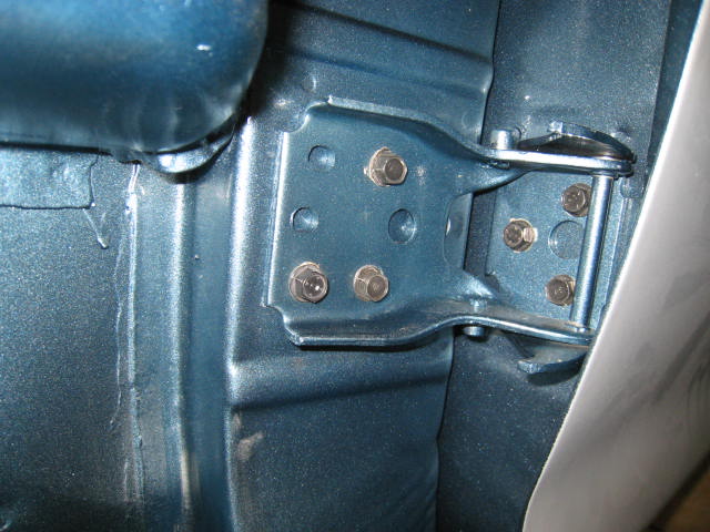 Blue 1976 Ford F-250 door hinge assembly, showing bolts and metal construction