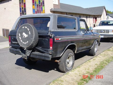 1979 Ford Bronco - This 1979 Ford Bronco is seen from the rear, parked next to another vehicle. The spare tire cover features the Ford Bronco logo.