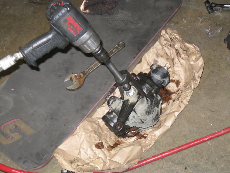 Air impact wrench, wrench, and a greasy steering box part on a mat