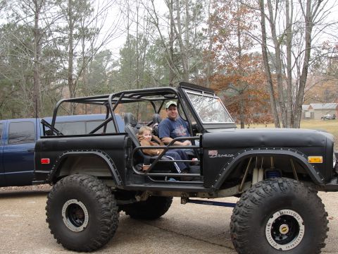 1967 Ford Mustang - This modified Ford Bronco features a full roll cage and massive off-road tires, with two occupants enjoying the ride.