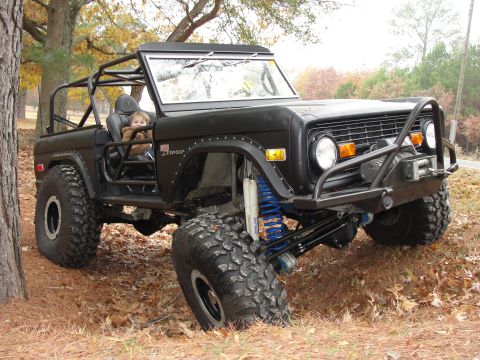 1967 Ford Mustang - Modified black Ford Bronco with a roll cage and off-road tires sits parked outdoors.
