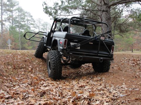 1967 Ford Mustang - This heavily modified off-road vehicle, likely a Ford Bronco, is shown from the rear on a leaf-strewn incline.