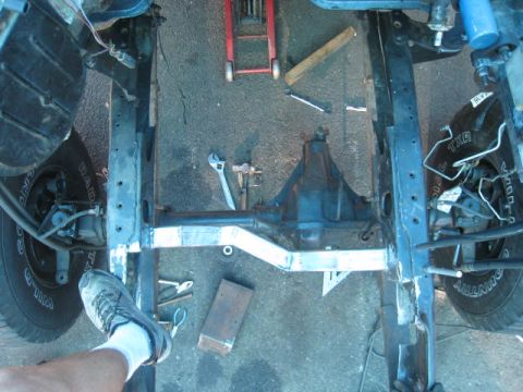 1976 Ford F-250 - The underside of a truck chassis is shown with suspension components and a differential during a repair process.