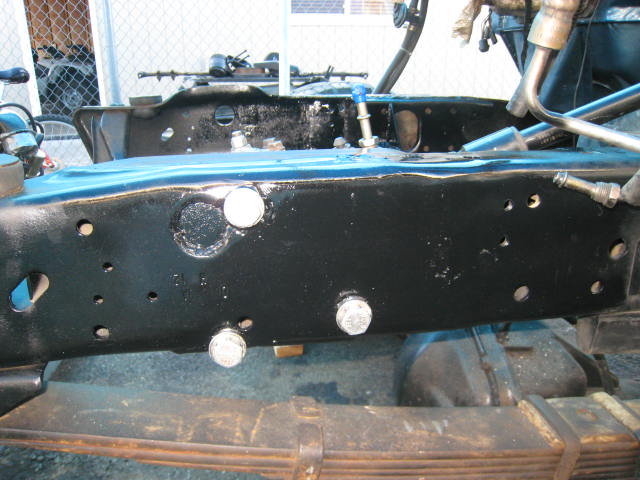 Close-up of a black truck frame with visible bolts and suspension parts