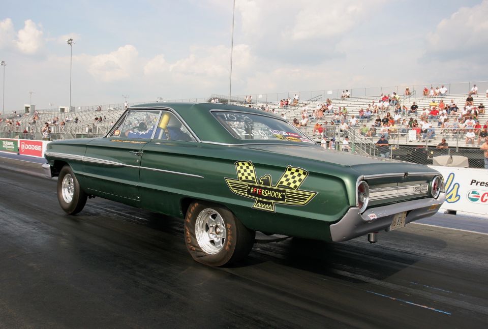 Green vintage drag car launching at a dragstrip