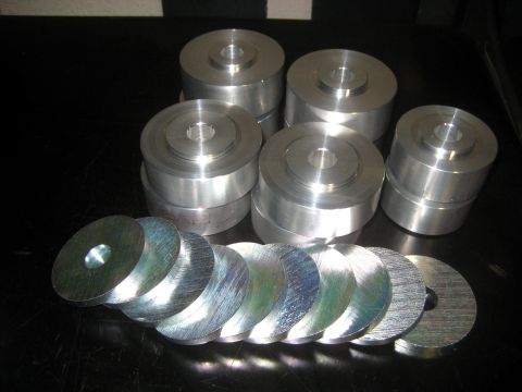 1996 Ford Bronco - Machined aluminum spacers and washers are laid out on a dark surface.