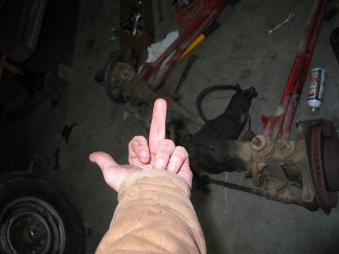 1984 Ford Bronco - A hand gives the middle finger in front of a disassembled front axle assembly, with Supermotors.net visible at the bottom right.