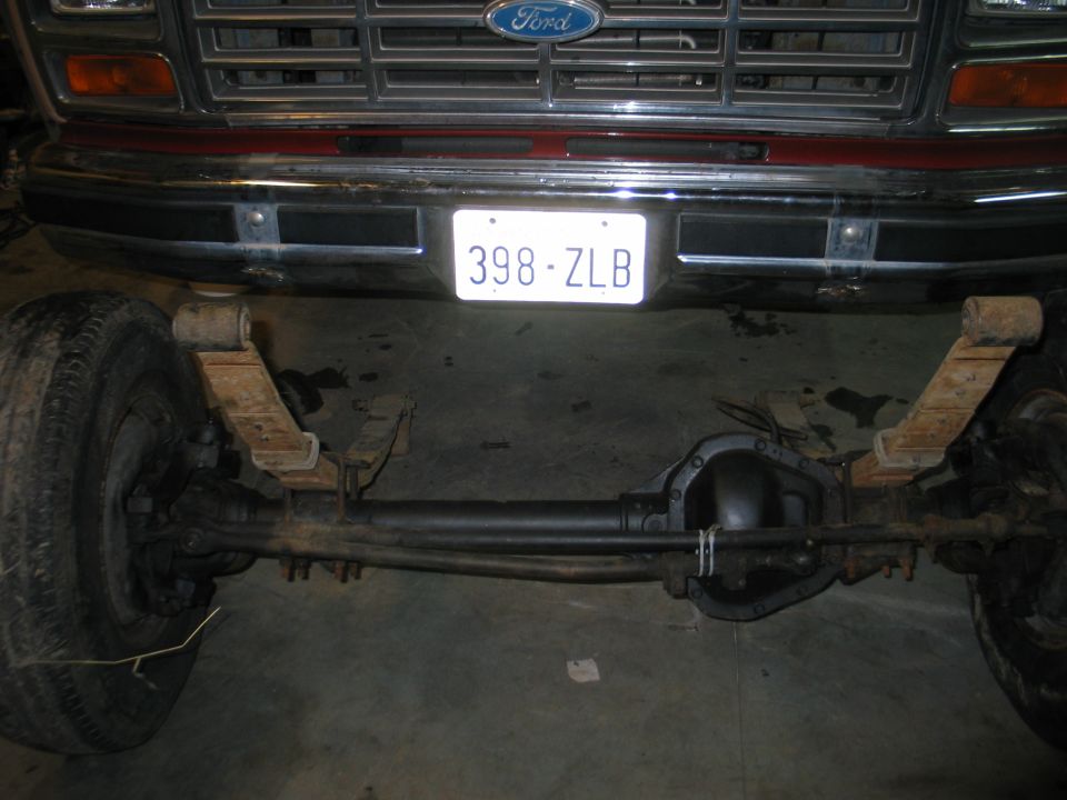 Ford truck front axle, leaf springs, and differential. Grille visible above